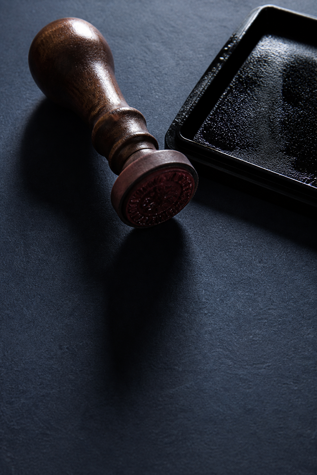 Rubber stamp handle beside a dark wet ink pad on blotter paper