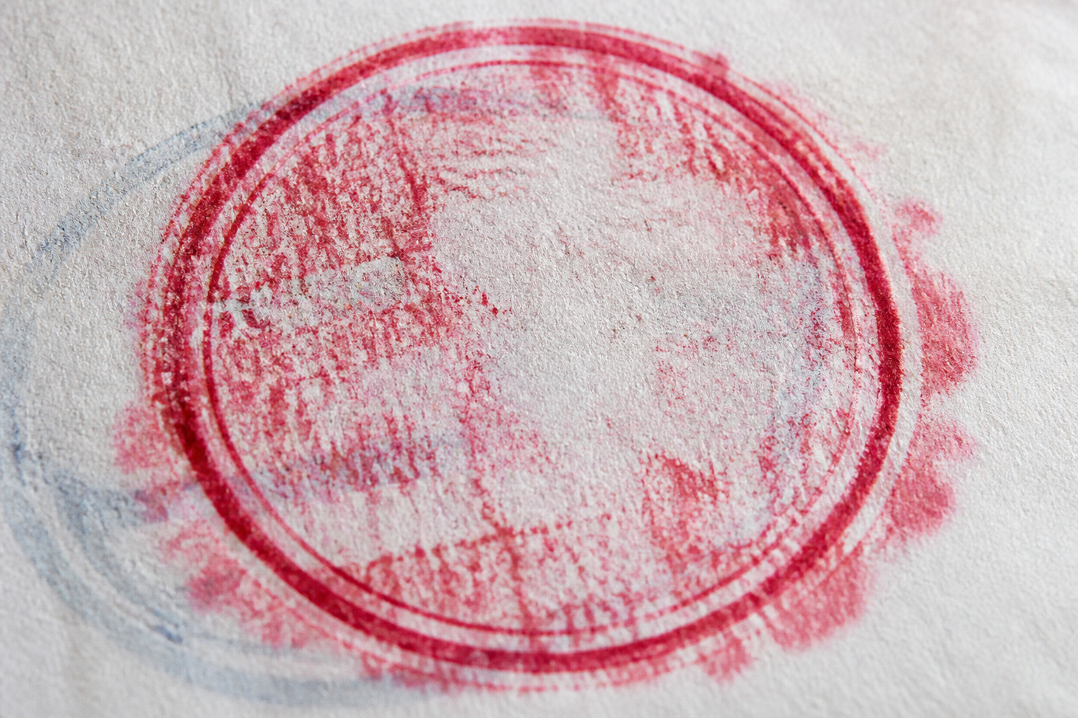 Circular smudged red rubber stamp impression on thin paper